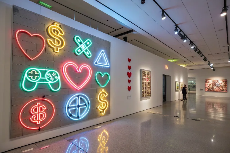 Contemporary art installation featuring neon lights and gaming symbols in gallery space
